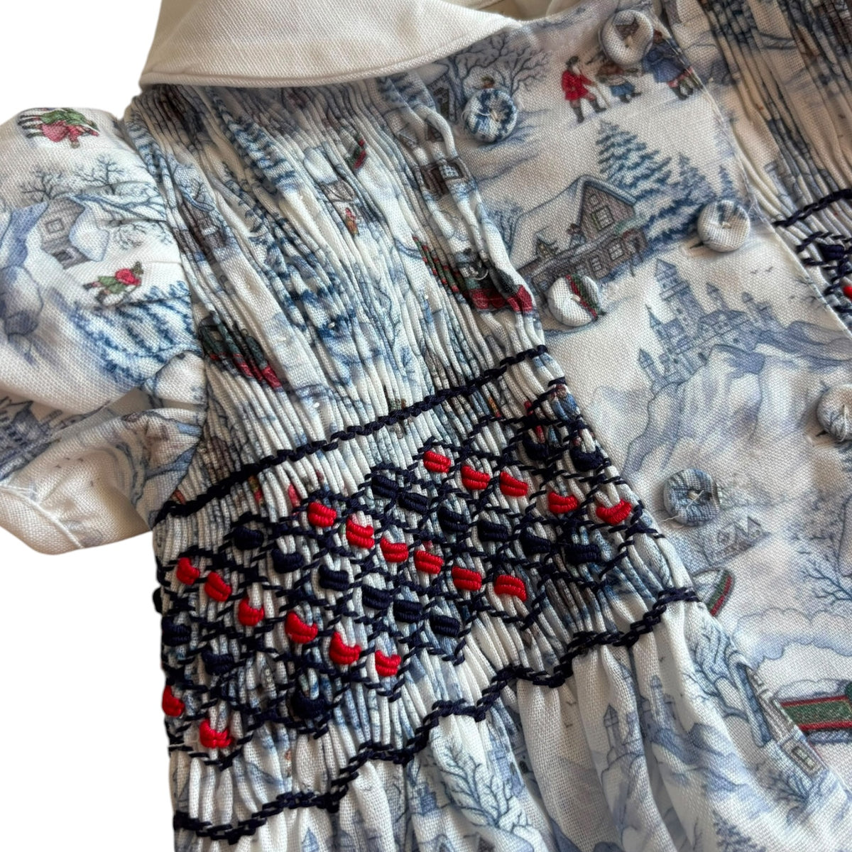 Close-up of black, red and white handsmocking on The Polar Express romper