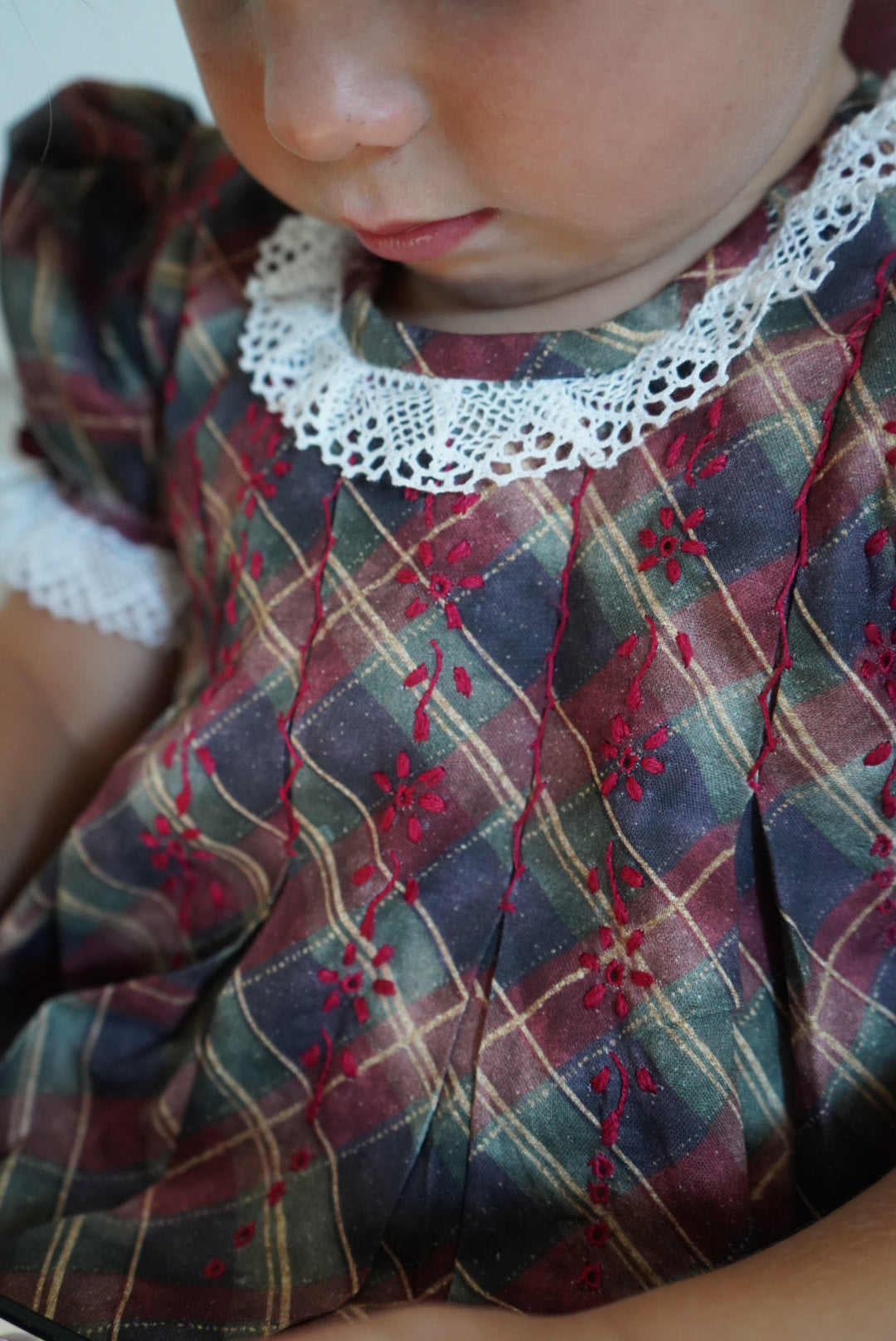 Close-up of ivory lace neckline and hand-embroidered detailing on Tartan Luxe Dress