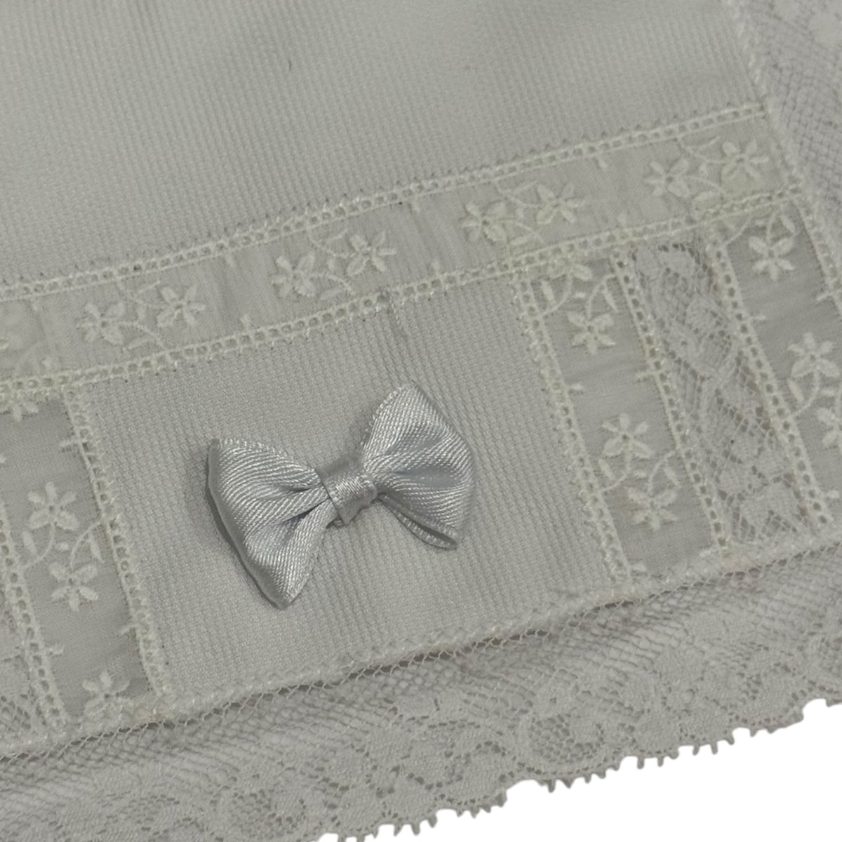 Close-up of white lace and embroidered bow detailing on Marilyn White Bib