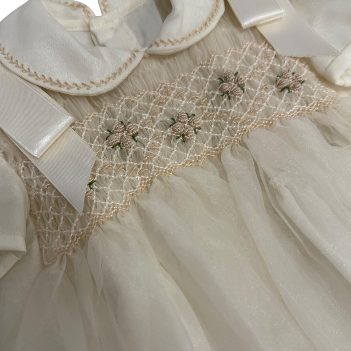 Close-up of tonal embroidery and handsmocking on Ernest Ivory Romper