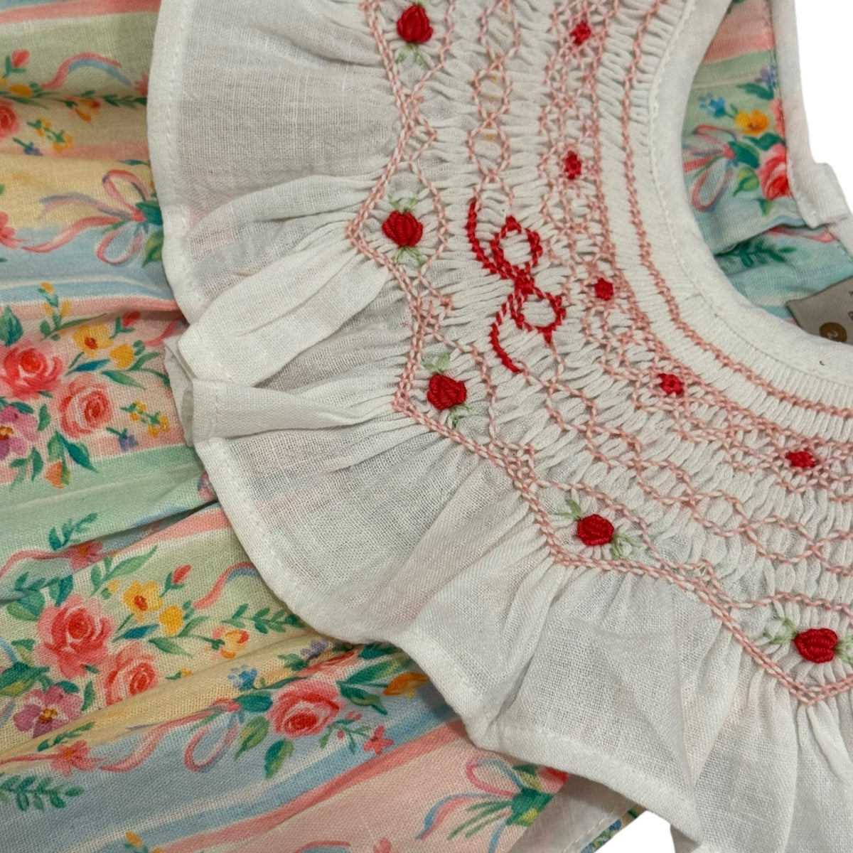 Close-up of ruffled ivory collar and red embroidered details on Eloisa Bow Handsmocked Dress