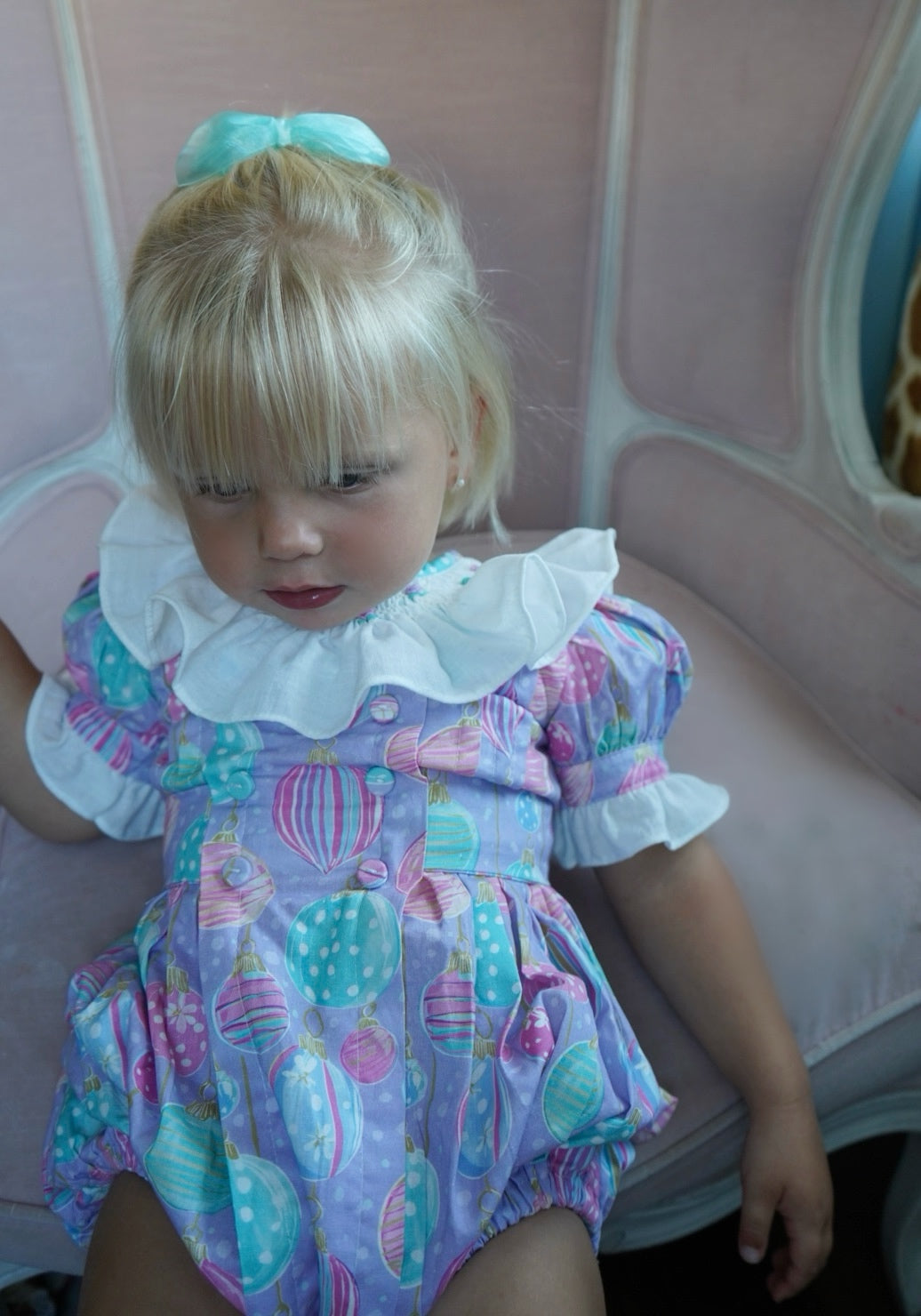 Girl wearing pastel ornament romper with ruffled ivory collar
