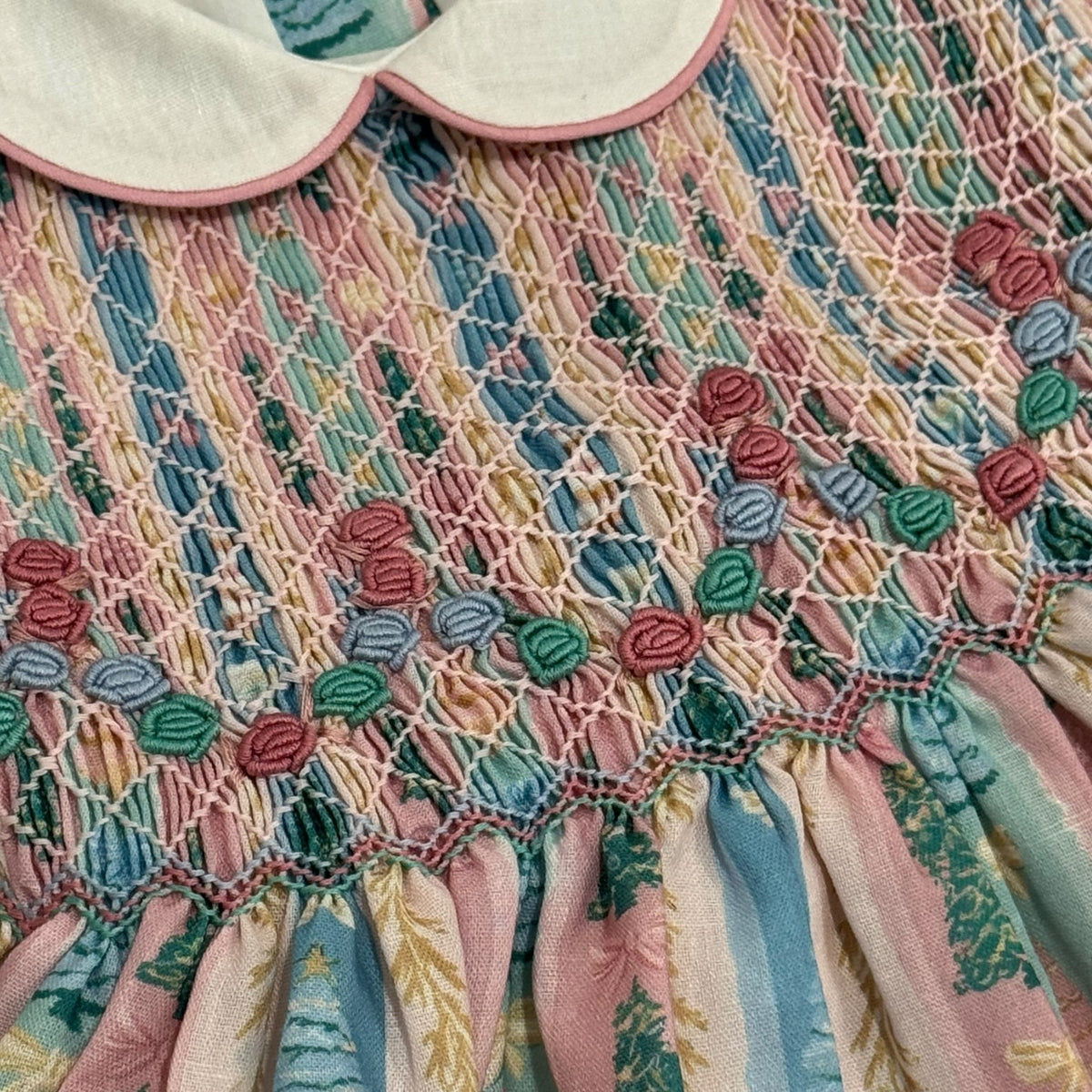 Close-up of pastel Christmas tree print and handsmocked bodice detailing