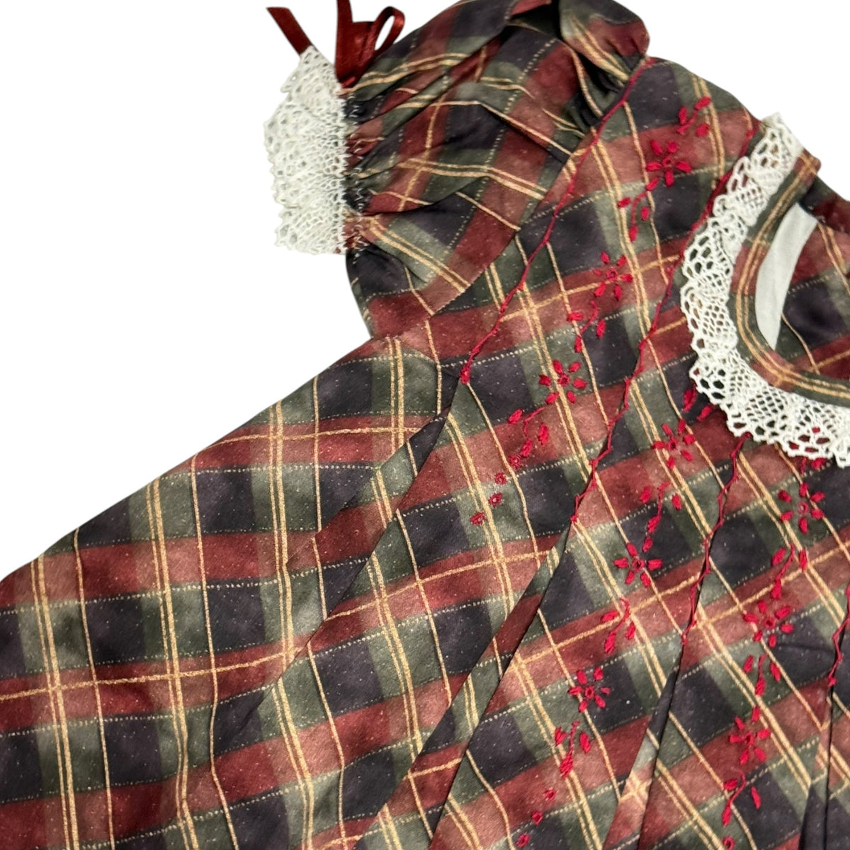 Close-up of burgundy, olive and neutral tartan fabric with embroidered details