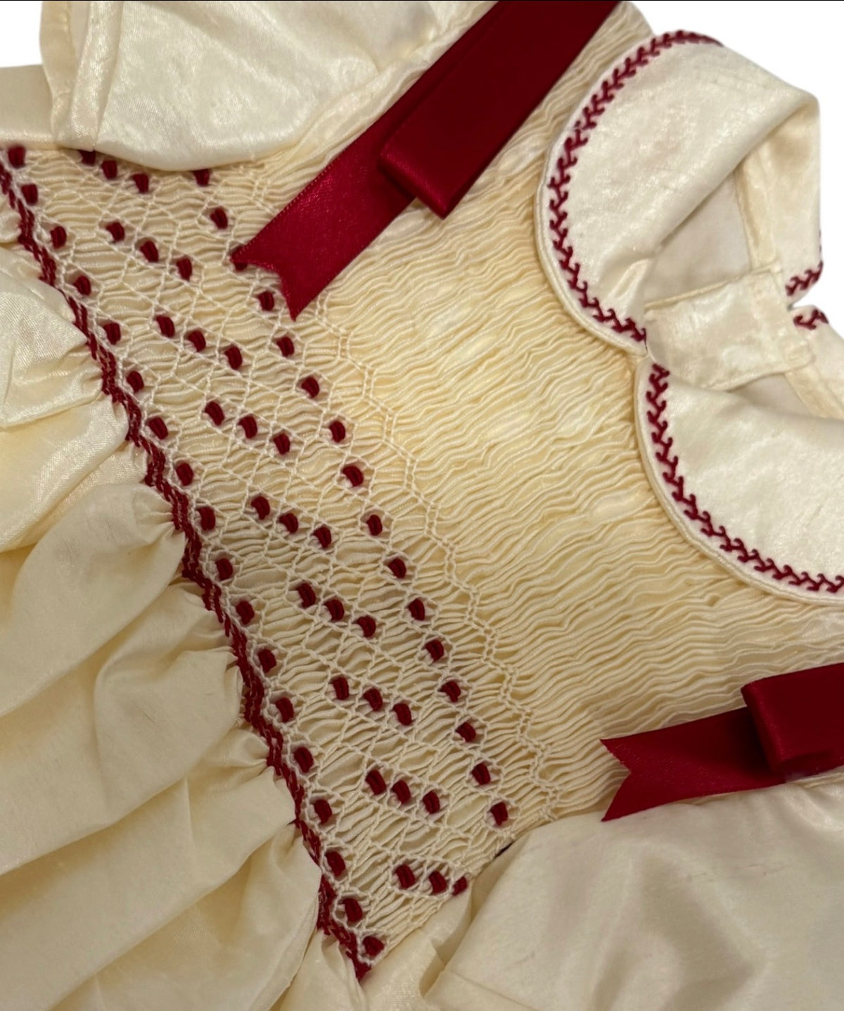 Close-up of burgundy handsmocking and velvet trim on Shantung Guinda Ivory Romper
