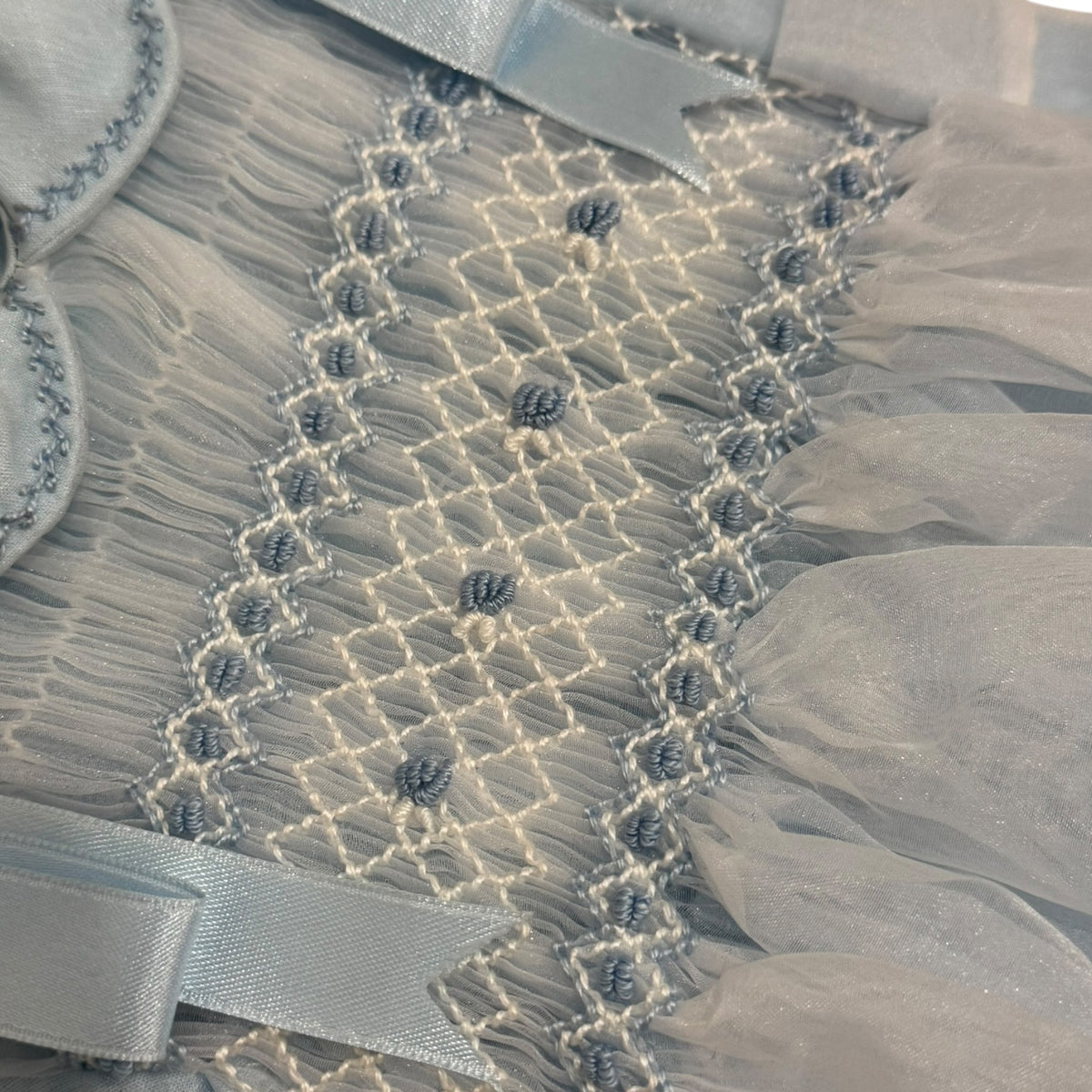 Close-up of intricate handsmocking on Humbert Ivory and Light Blue Romper