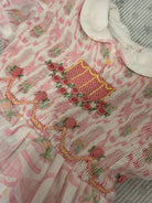 Close-up of Birthday Pink Cake and Bows Romper with handsmocked cake and floral detailing

