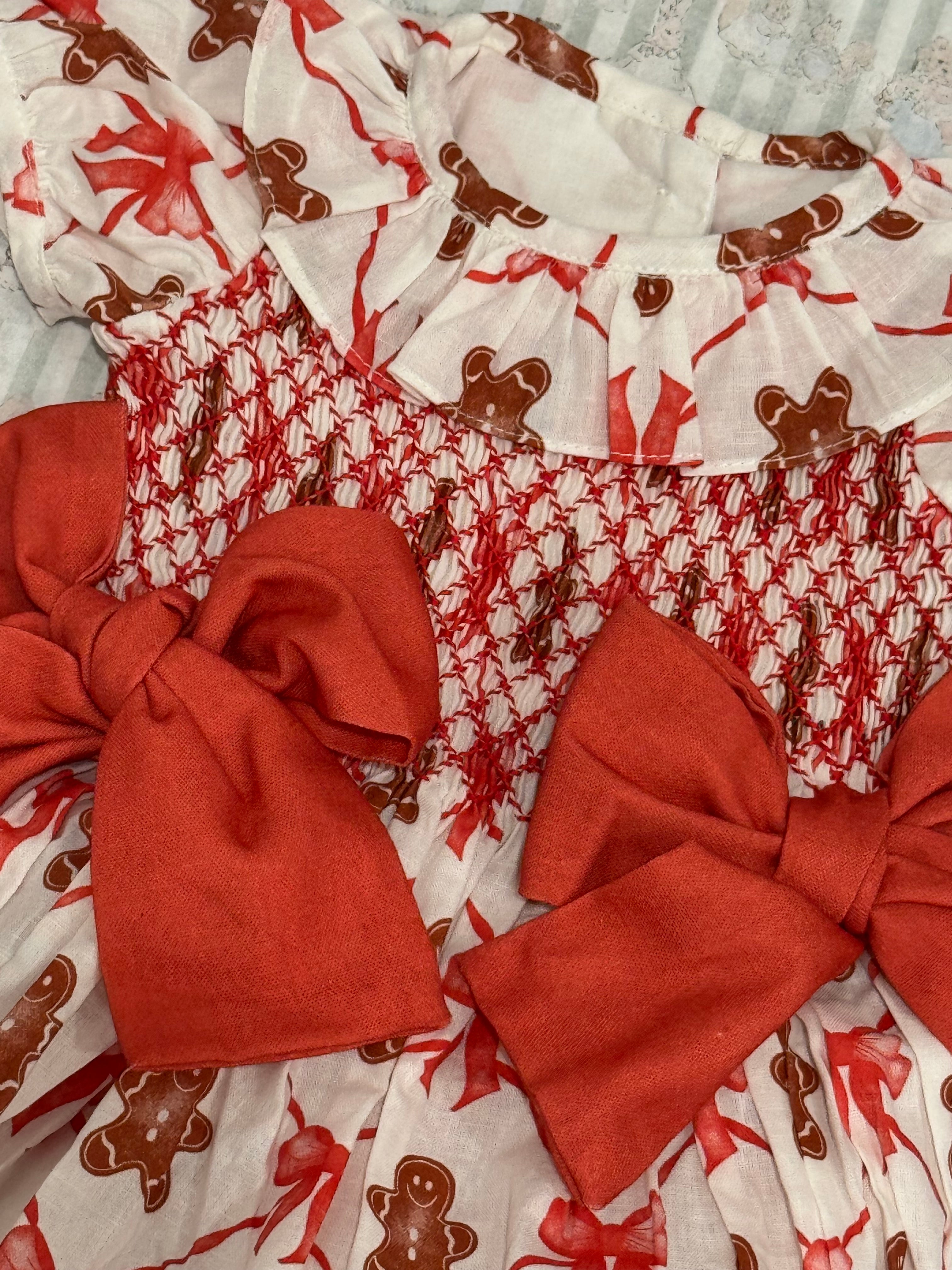 Close-up of gingerbread cookie print and red smocked detailing on romper