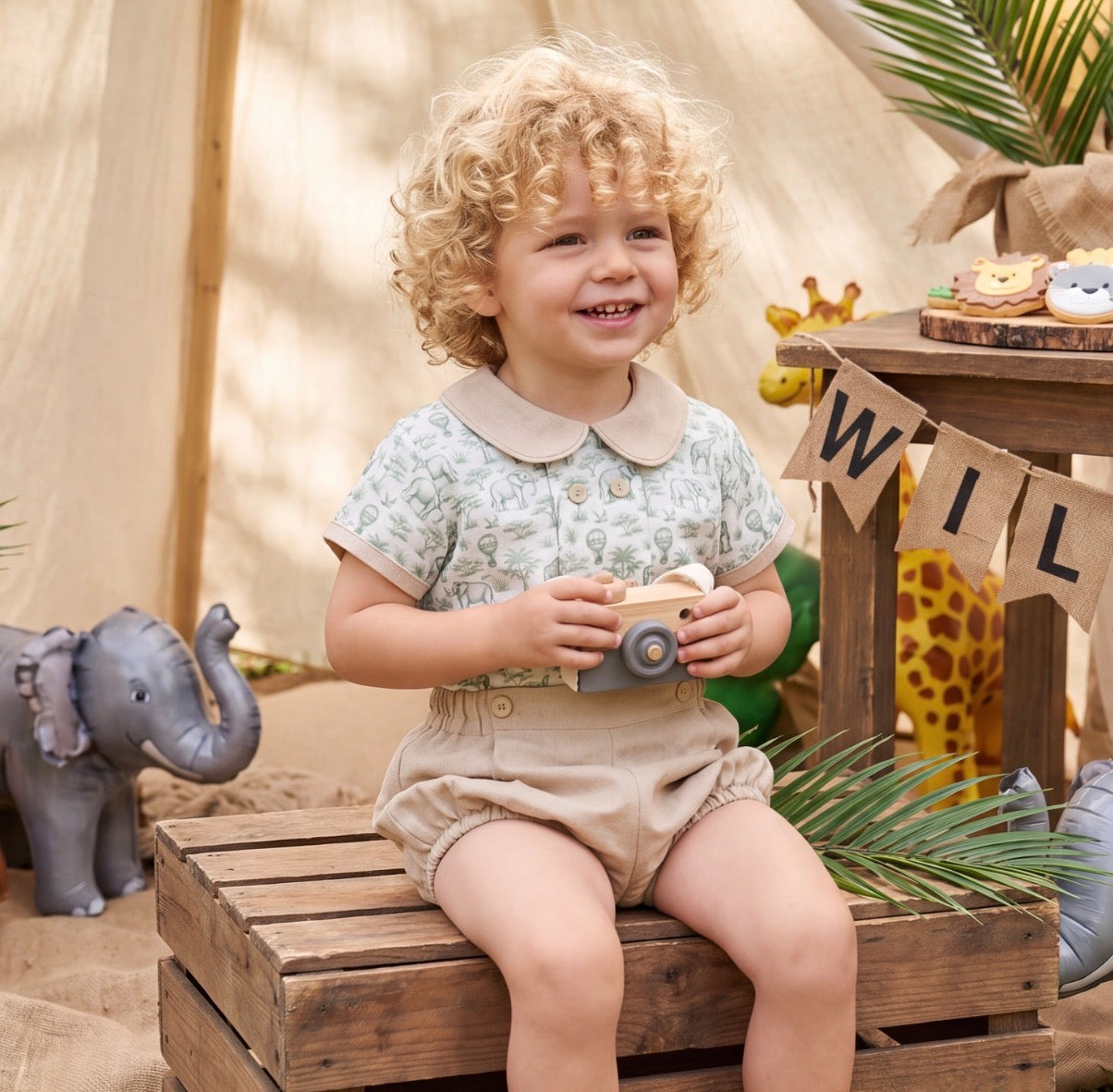 Boy wearing Safari Green Boy Set with green toile shirt and beige bloomer shorts