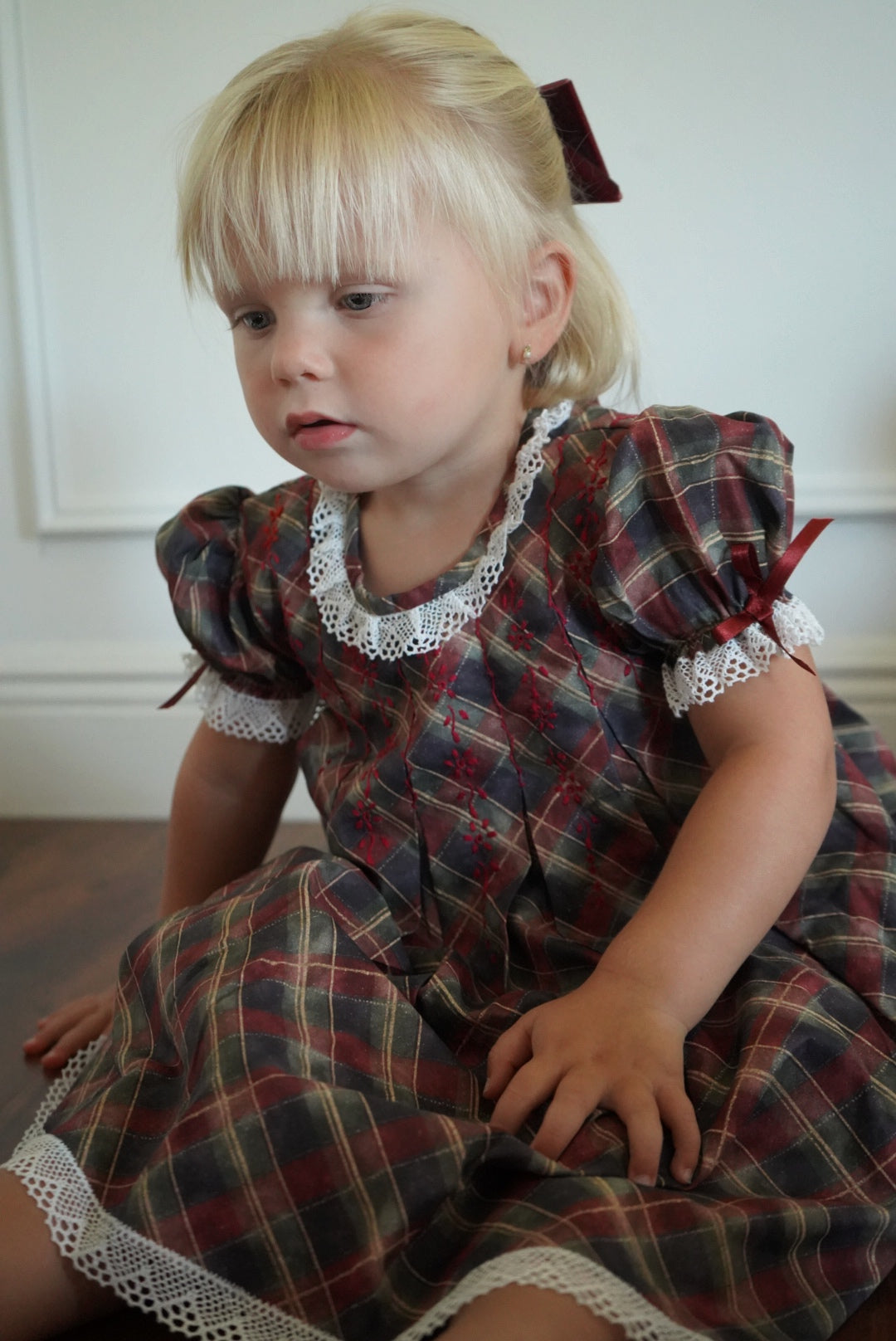 Girl wearing Tartan Luxe Handembroidered Dress with burgundy ribbon sleeve bows