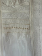 Close-up of ivory lace and handsmocking on Regina Luxe Dress