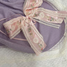 Close-up of pink floral bow on Aida Rose Luxe Purple Knitted Blanket