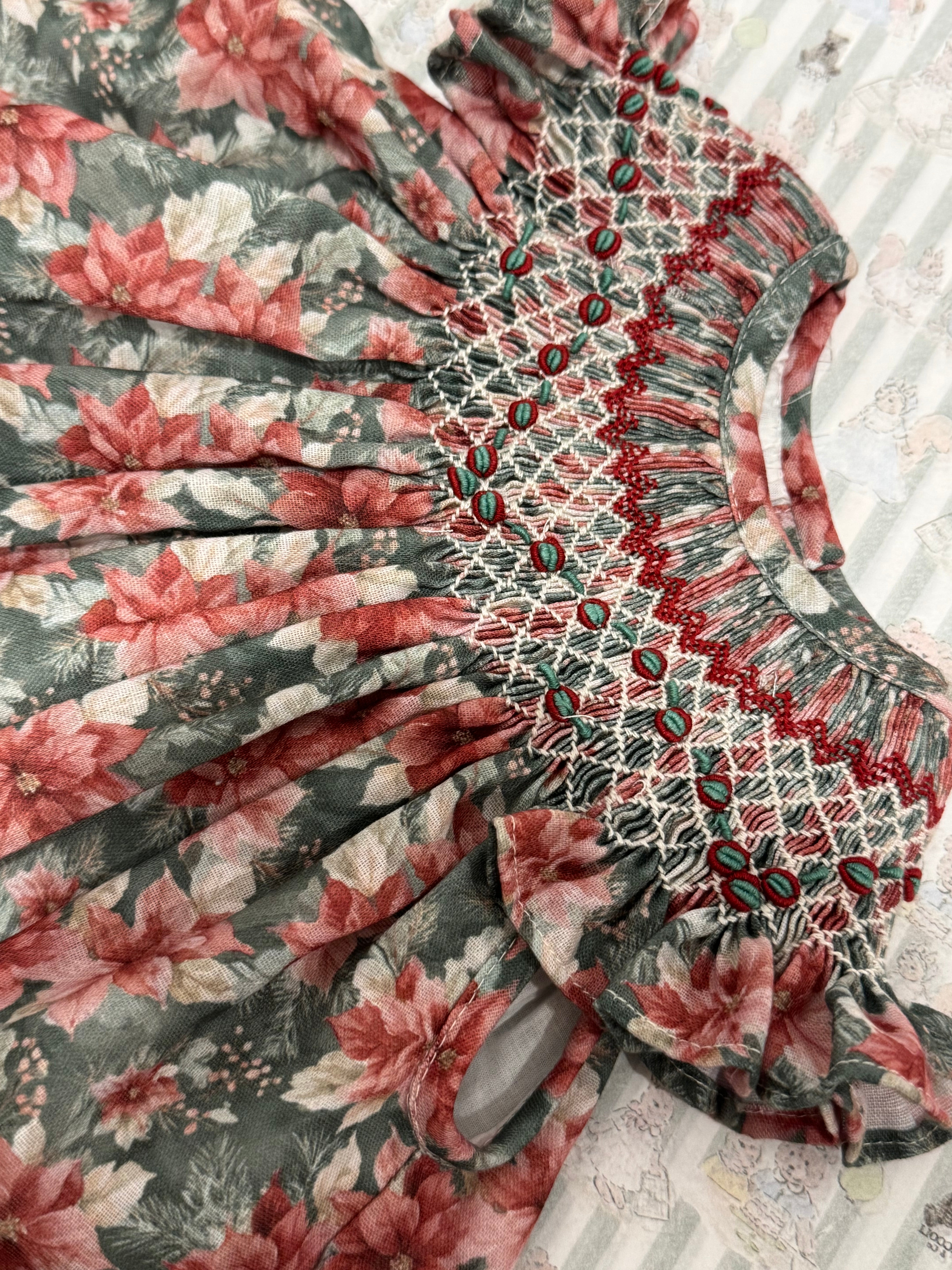 Close-up of Christmas floral print and handsmocking on Bishop Dress