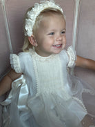 Girl wearing Pauli Organza Handmade Flowers Headwrap / headband and Emma Luxe Ivory Handsmocked Dress 