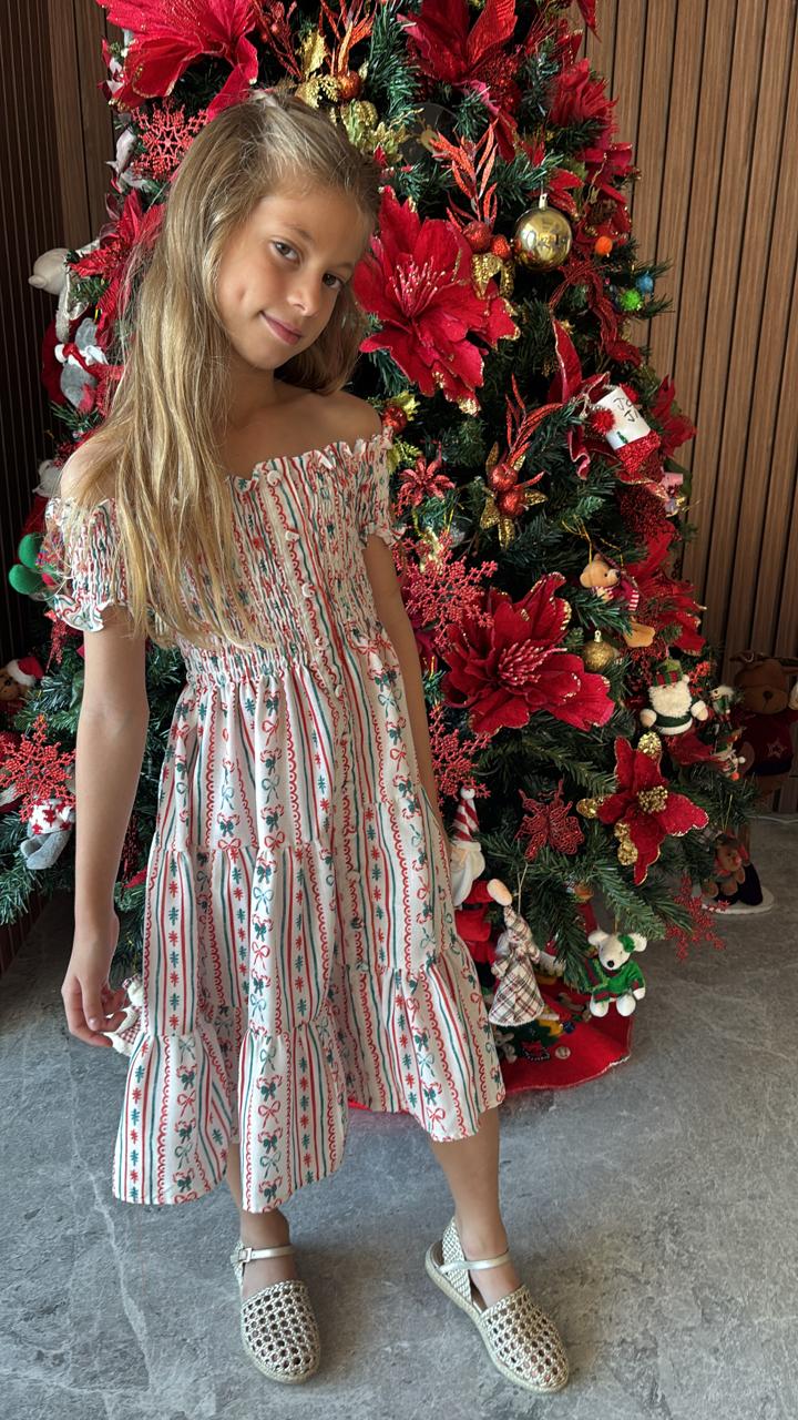 Girl wearing Piccoli & Co Christmas nap dress beside a decorated Christmas tree