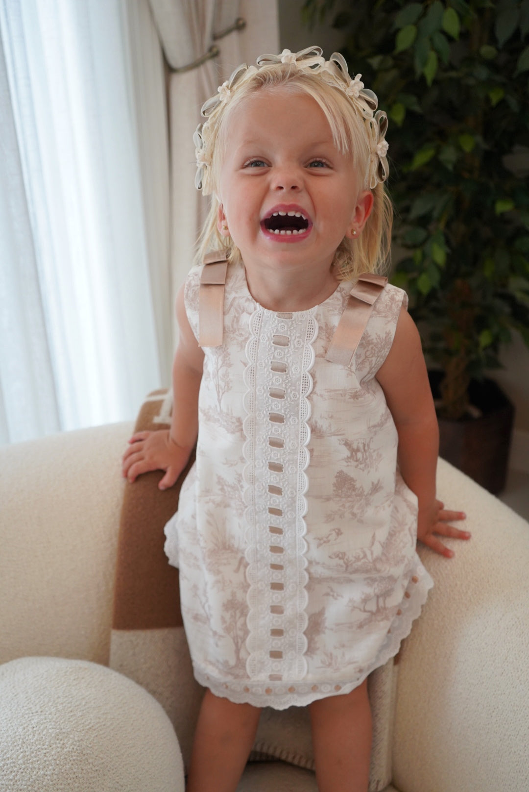 Girl wearing TPWC Toile Beige Ribbon Dress in soft neutral toile print